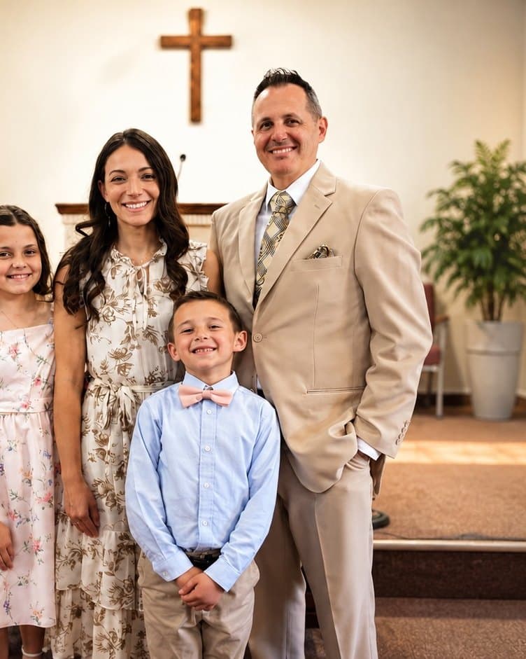 Pastor Brandon Bankert, his wife and their children smiling in front of the pulpit and the cross